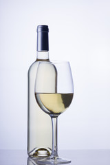 High glass with still white wine and wine bottle