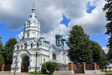 Building of white orthodox church The Holy Apostles Peter and Paul with grey domes against the white cross shaped cloud on the sky, Podlasie, Poland - 166378228