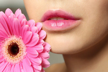 Young woman with beautiful lips and gerbera flower near face, closeup