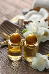 Bottles with coconut oil and flower on tray, closeup