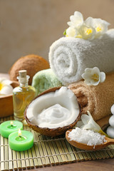 Beautiful spa composition with coconut body care products on bamboo mat