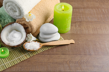 Beautiful spa composition with desiccated coconut in spoon and stones on bamboo mat