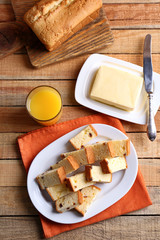 Plate with delicious cake, butter and glass of juice on wooden table