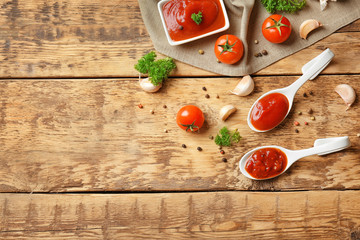 Ceramic spoons with tomato sauce and spices on wooden table