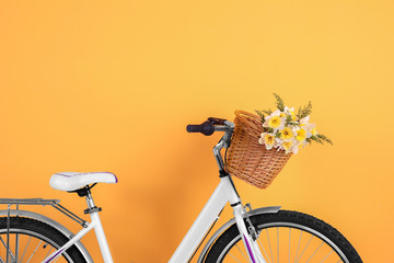 Bicycle with basket of beautiful flowers on color background © Africa Studio