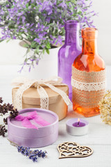 Obraz na płótnie Canvas Purple flowers and lit candle on white table