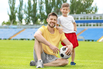 Obraz premium Dad and son with soccer ball in stadium