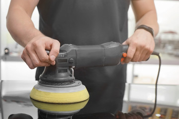 Man polishing car with power buffer machine in store