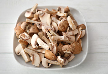 Plate with mushrooms on white wooden table