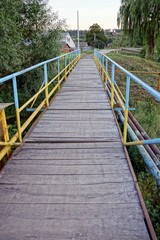 Fototapeta na wymiar Сельский старый мостик через реку возле деревьев и травы