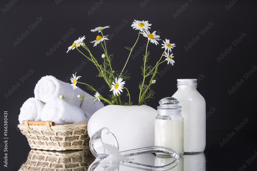 Wall mural Spa. Chamomile in a vase, three white towels rolled into a roll lie in a basket. Two cans of cream. Salt in a transparent scoop.