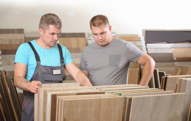 Carpenter helping his customer to choose materials in hardware store
