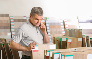 Mature man choosing laminate samples in hardware store