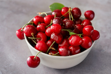 Plate with fresh ripe cherries on grey background