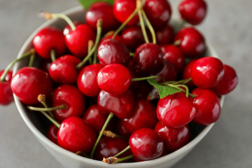 Bowl with fresh ripe cherries on grey background