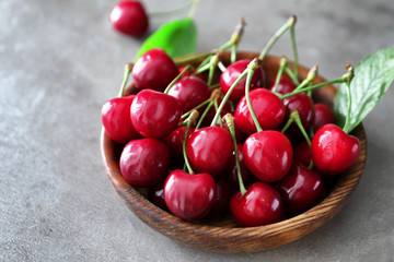 Bowl with fresh ripe cherries on grey background