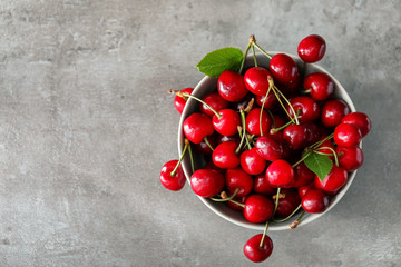Bowl with fresh ripe cherries on grey background