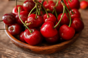 Wooden plate with fresh ripe cherries on table