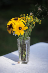lato w ogrodzie - bukiet kwiatów na stole z białym obrusem