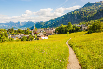 Beautiful view of green alpine meadow with a walking path and village St. Gilgen, Austria