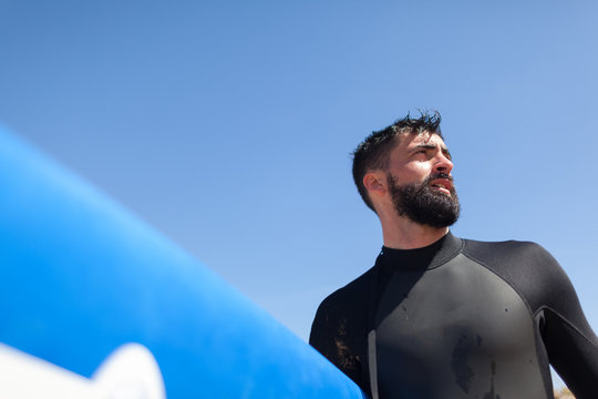 Man Holding Surfboard Wearing a Wetsuit