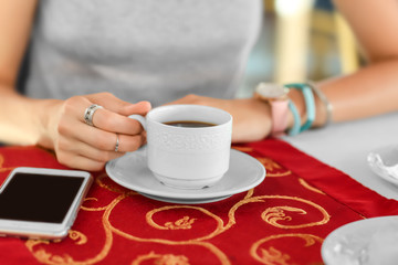Young woman drinking coffee in cafe, closeup