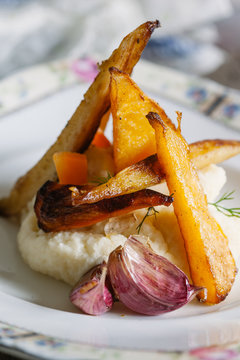 Closeup of a plate of roasted vegetables with celeriac mash.