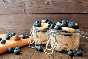 Overnight oats with fresh blueberries and bananas in a snap lid jar on a rustic wood background