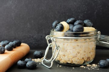 Overnight oats with fresh blueberries and bananas in a jar against a dark background