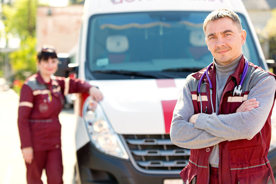 Man doctor with colleague paramedic on ambulance car background