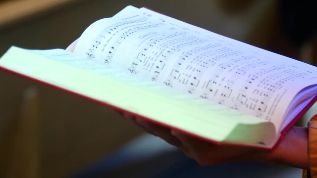 A parishioner holds a hymn book open.