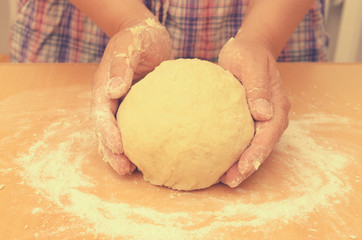 A woman kneads a homemade dough for pizza production.