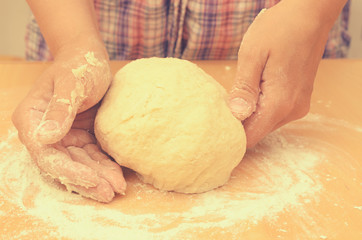 A woman kneads a homemade dough for pizza production.