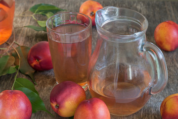 Peach compote in a glass and a jug on a wooden table