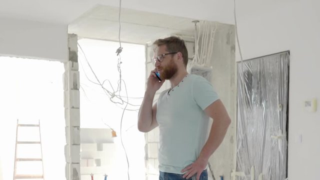 Architect standing in the new flat and talking on cellphone, steadycam shot
