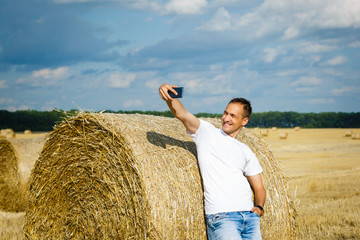 Naklejka na ściany i meble Young man taking selfie from mobile phone while standing on field