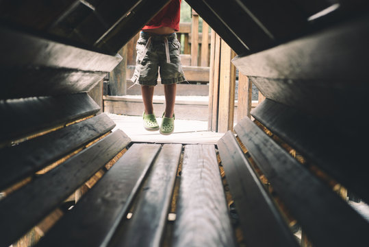 child hanging from a wooden playground structure