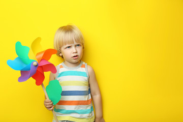 Portrait of little boy with rainbow whirligig on yellow background