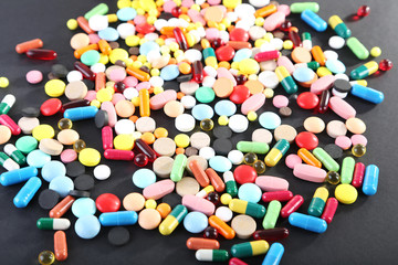 Fototapeta na wymiar Different colorful pills on black background