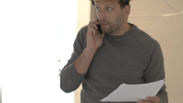 Architect wearing helmet and talking about the project on cellphone, steadycam shot
