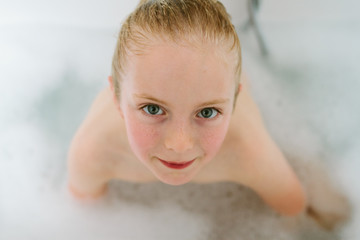 A little girl with wet hair in a bubble bath