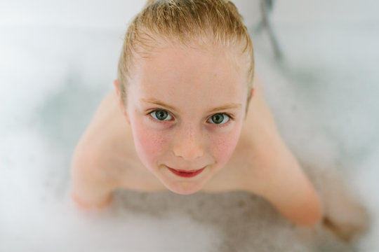 A little girl with wet hair in a bubble bath