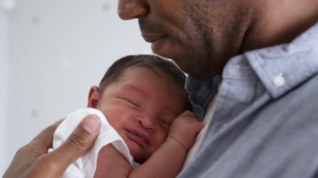 Father Cuddling Sleeping Newborn Baby Son In Nursery