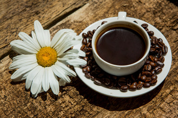 Coffee cup and fried Coffee beans on a wooden table with beautiful white flowers on a wood background