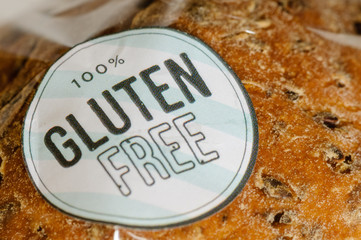 "100% Gluten Free" sticker on a loaf of brown seeded bread.