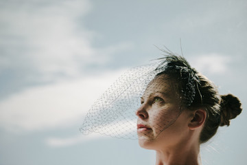 woman wearing a black veil looks up toward the sky