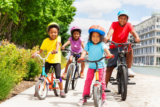 Happy African children in helmets riding bikes