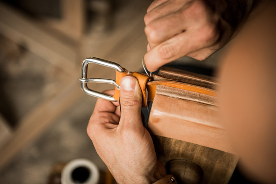Man sewing leather belt