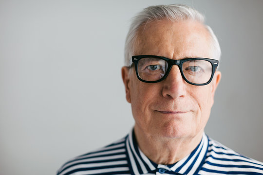 Portrait of an elderly man with rimmed glasses looking at camera.