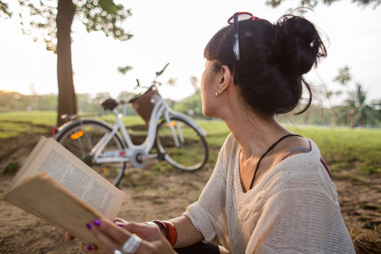 Asian woman reading a book in a park